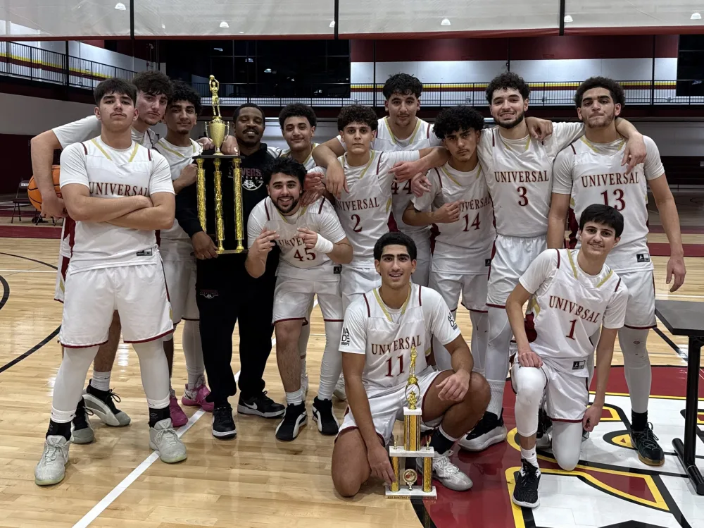 Universal Stars boys basketball team in school jerseys posing with trophies on the court